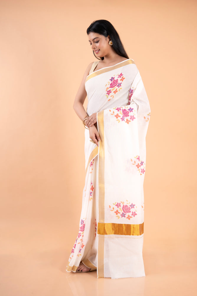 Woman wearing a white saree with floral patterns on a beige background