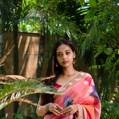 Woman in a colorful saree standing among lush greenery with yellow flowers.