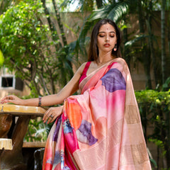 Woman in a colorful saree sitting outdoors with greenery in the background