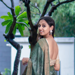 Woman in a long dress standing under a tree with yellow flowers in a garden setting