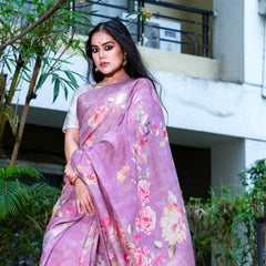 Woman wearing a pink saree with floral patterns standing outdoors.