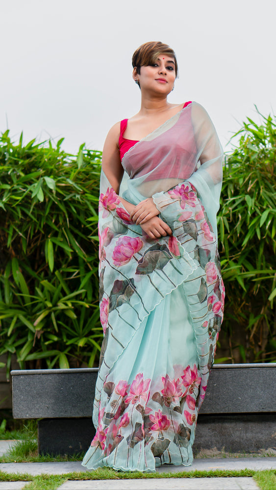 Woman wearing a floral saree standing outdoors with greenery in the background
